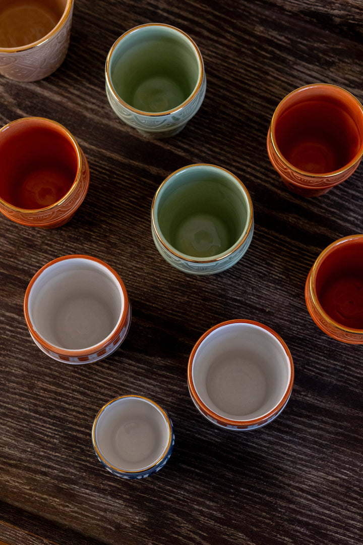Collection of ceramic cups with different colors on a wooden surface