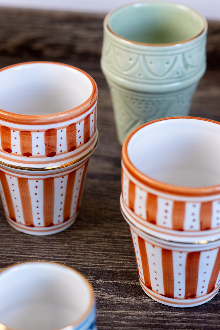 Set of ceramic pots with striped patterns on a wooden surface