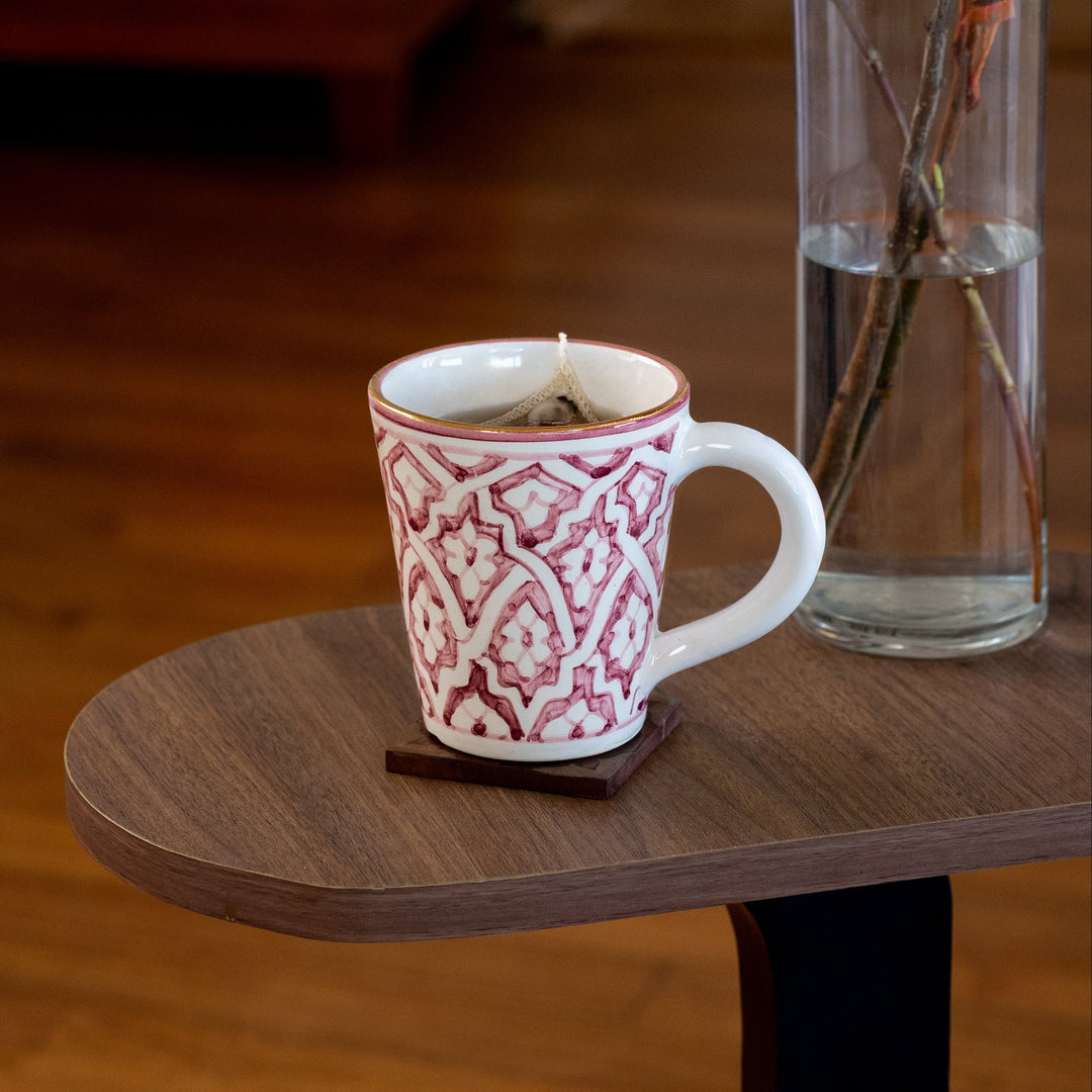 Decorative mug with intricate patterns on a wooden table, with a blurred background of a cozy living room.
