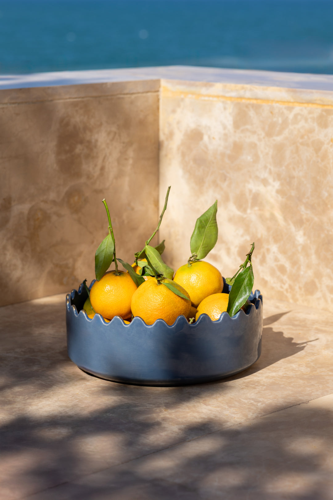 Blue ceramic bowl with lemons on a stone surface with a blue background