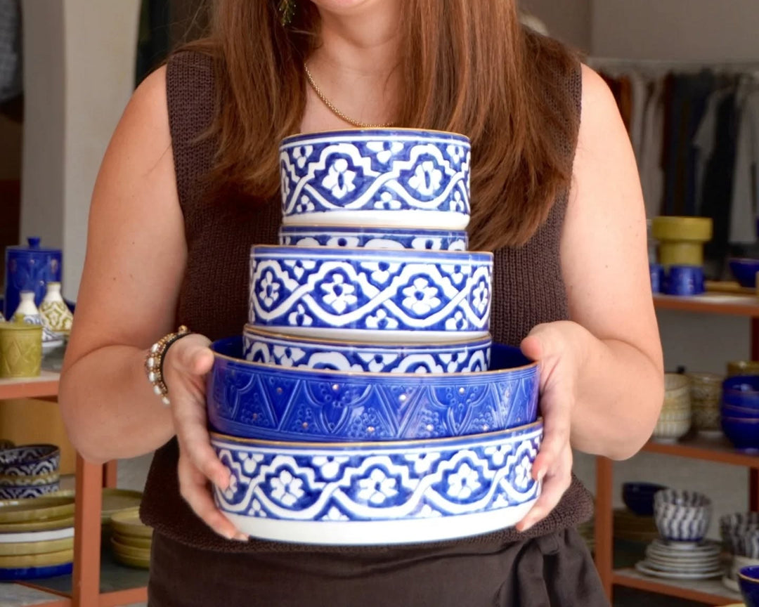 Person holding a set of blue and white ceramic bowls with intricate patterns.