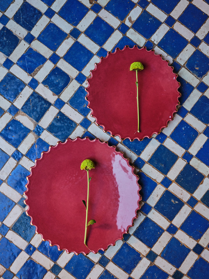 Handmade burgundy ceramic plate with gold rim and scalloped edges.