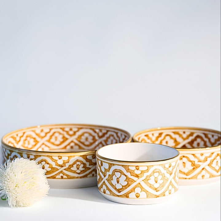 Three ceramic bowls with gold and white patterns on a light gray background