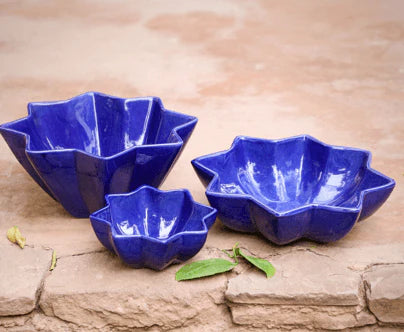 Set of three blue ceramic bowls on a stone surface
